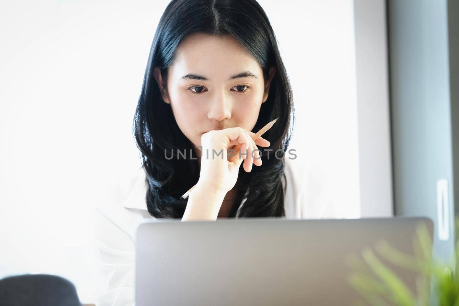 Female employees are working at home through computers to maintain social distancing to reduce the spread of coronavirus. by Manastrong