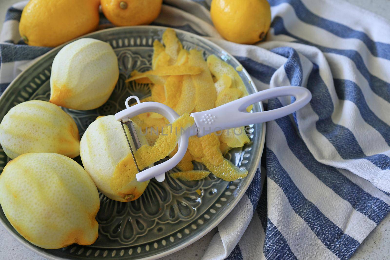 Lemon fruits and peeled strips for zest or making limoncello. Peeler, lemons and zest. Copy space, selected focus by Proxima13