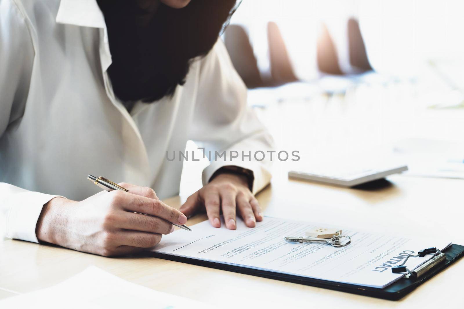 The customer is holding a pen and is reading the housing purchase contract before signing it