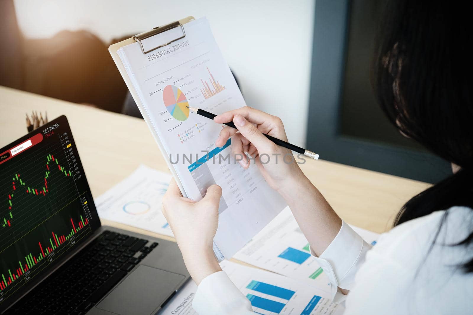 Business owner holding a pencil pointing to financial documents to analyze the profits of third parties to invest in company stocks. by Manastrong