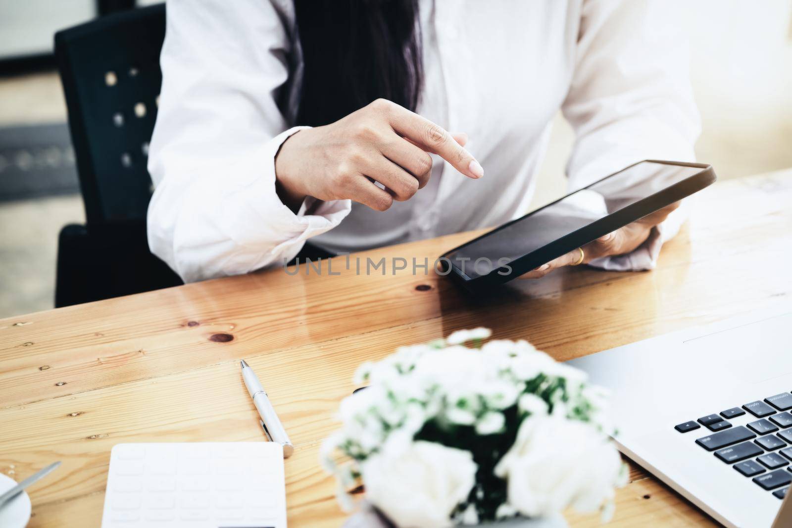 Woman using ipad for working in office room. by Manastrong