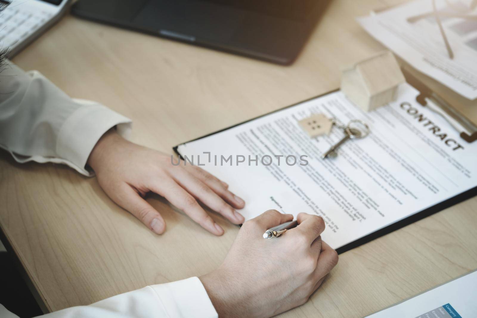 The customer is holding a pen and is reading the housing purchase contract before signing it
