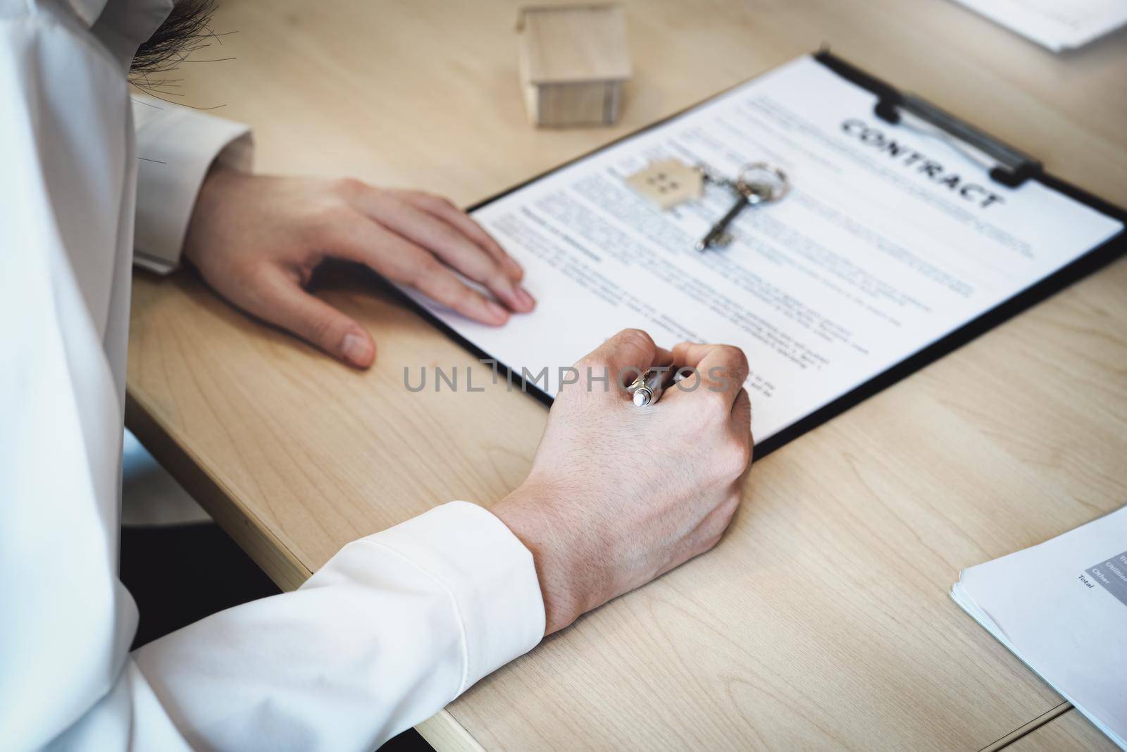 The customer is holding a pen and is reading the housing purchase contract before signing it