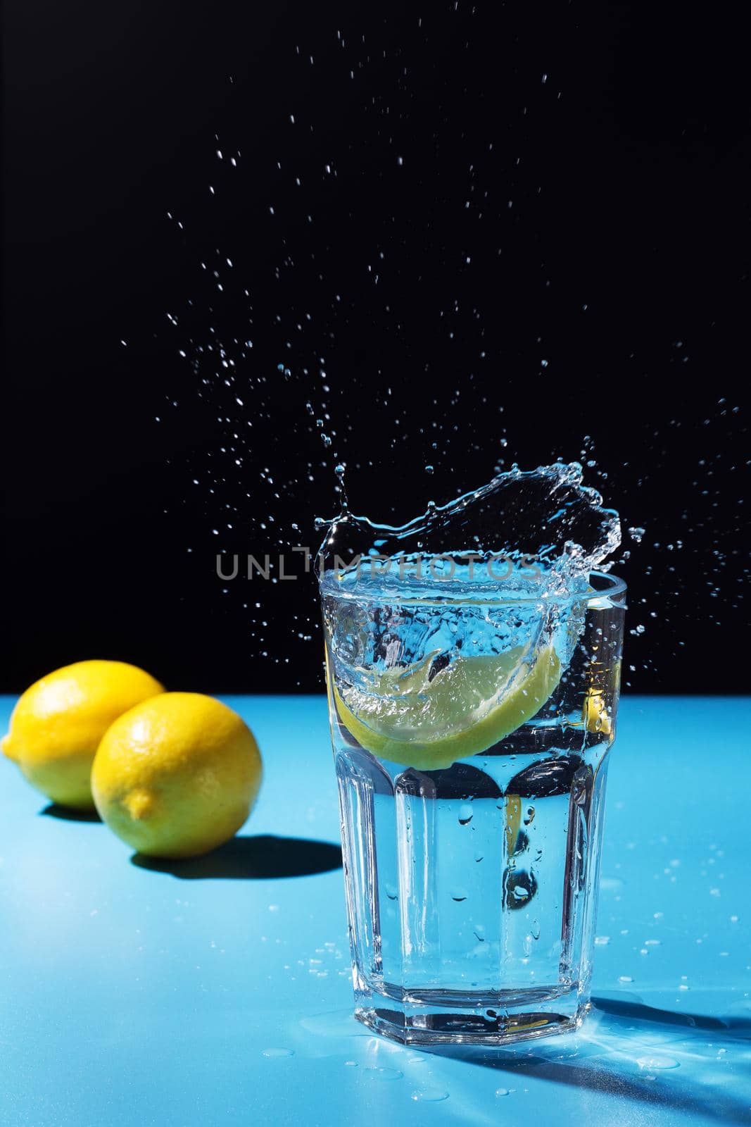 Water splash with lemon on blue and black background by lara29