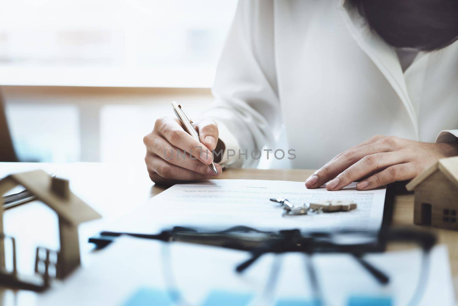 The customer is holding a pen and is reading the housing purchase contract before signing it. by Manastrong