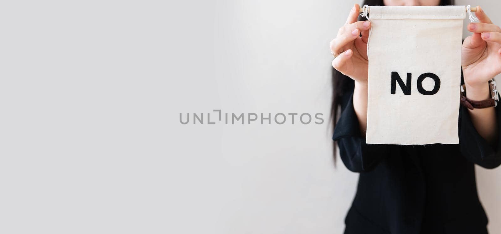 Young business woman in a black suit shows a blank white billboard on a white isolated background. There is no inscription on the poster. Concept for business and advertising. Banner