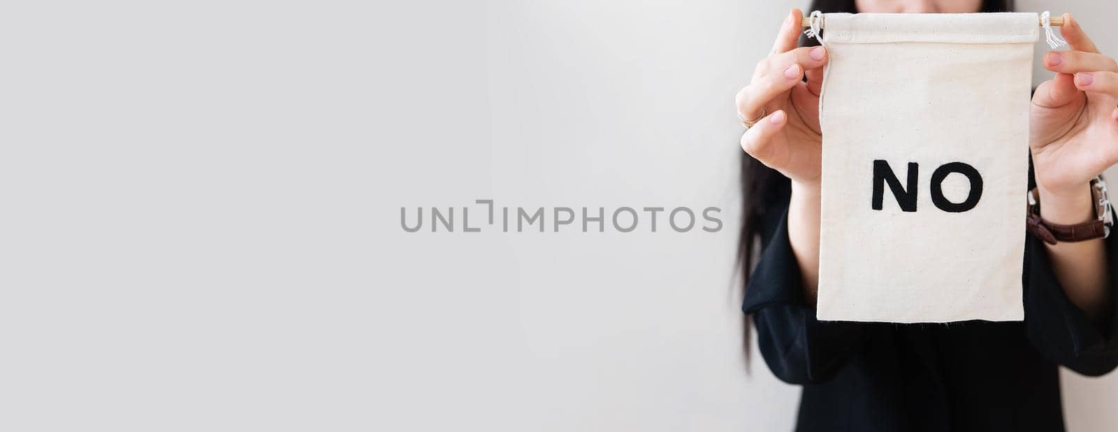 Young business woman in a black suit shows a blank white billboard on a white isolated background. There is no inscription on the poster. Concept for business and advertising. Banner