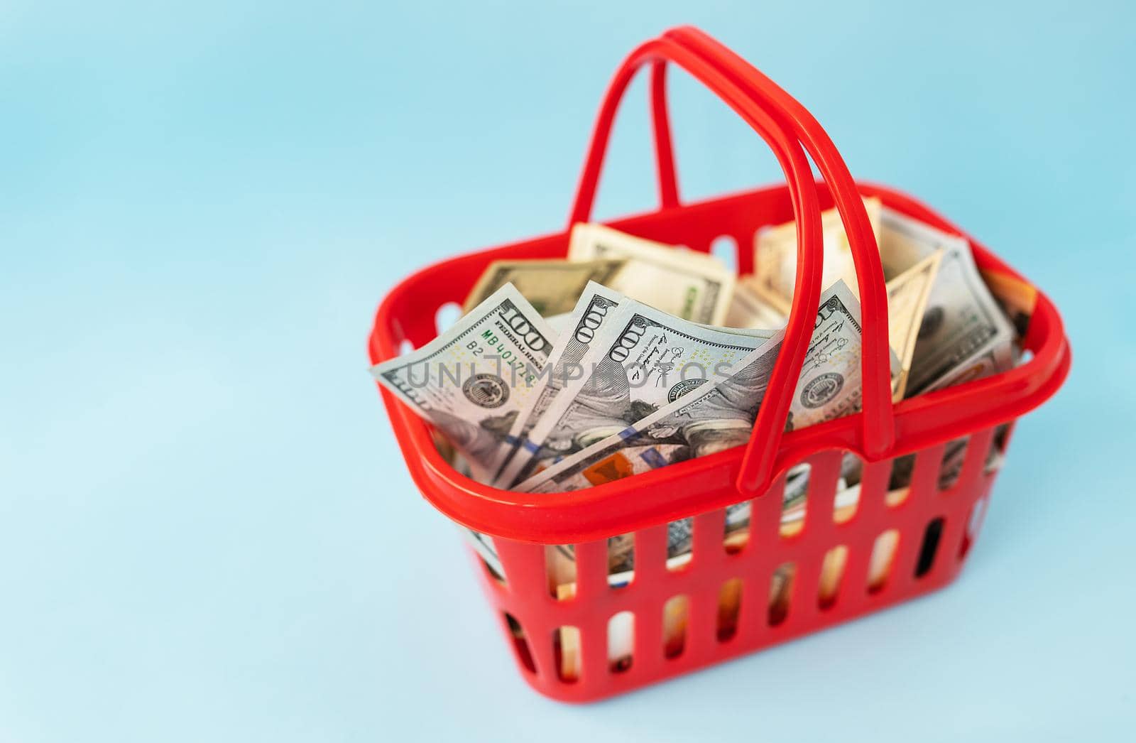 Red grocery cart with many 100 dollar bills inside. The concept of rising prices, inflation, economy, family expenses, family budget