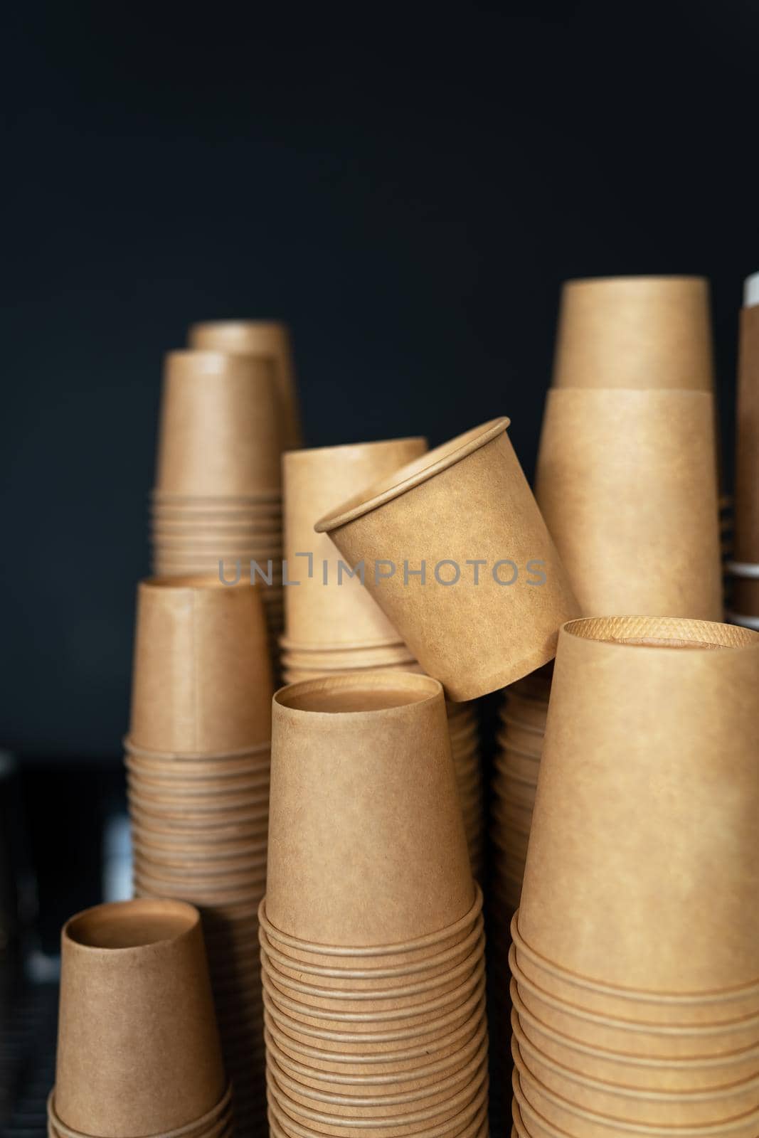 Disposable paper cups on a black background stand in a coffee shop. Barista work. The concept of cooking coffee, coffee to go