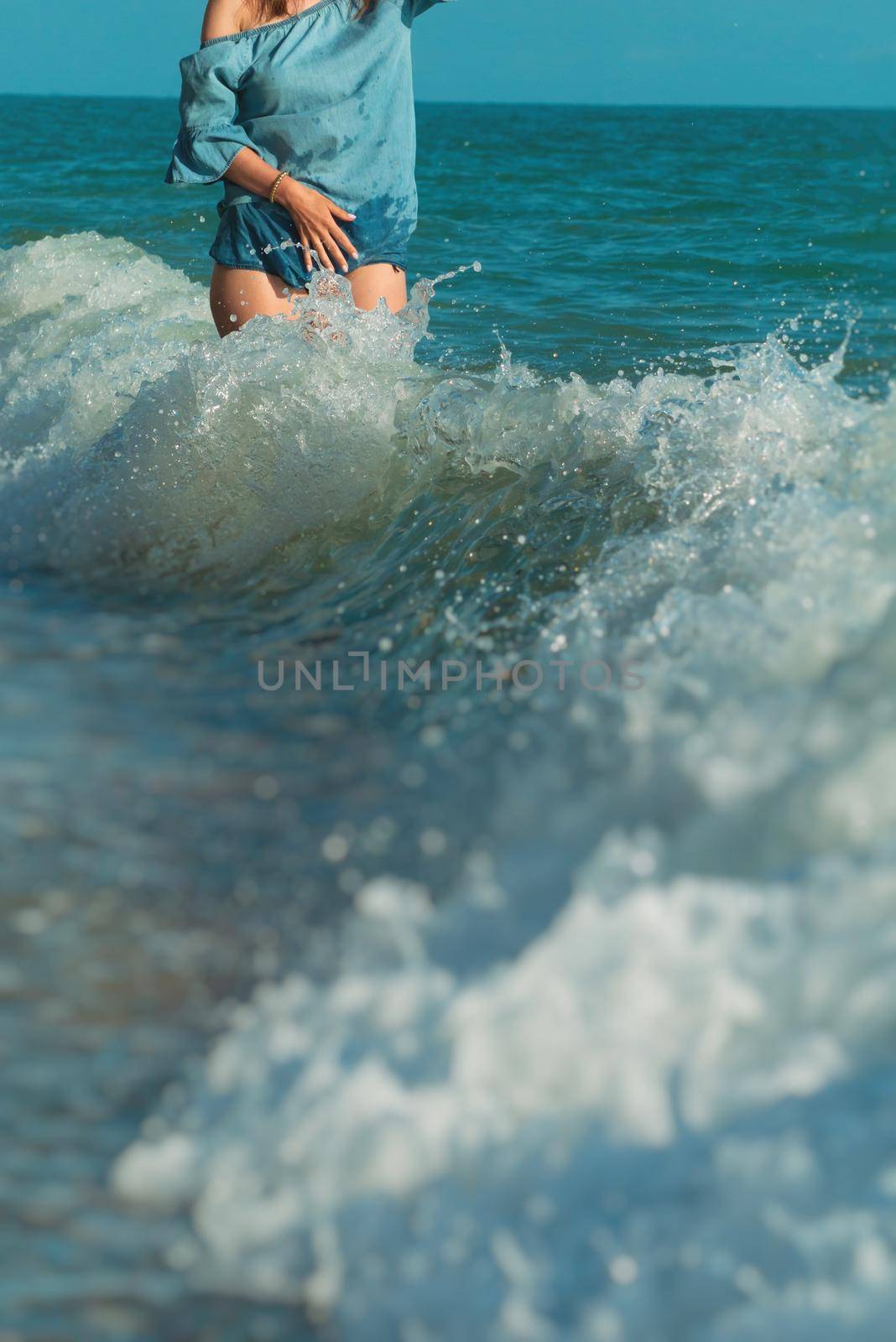 the beautiful girl in a hat in summer on the seashore happily walks on the water with emotions