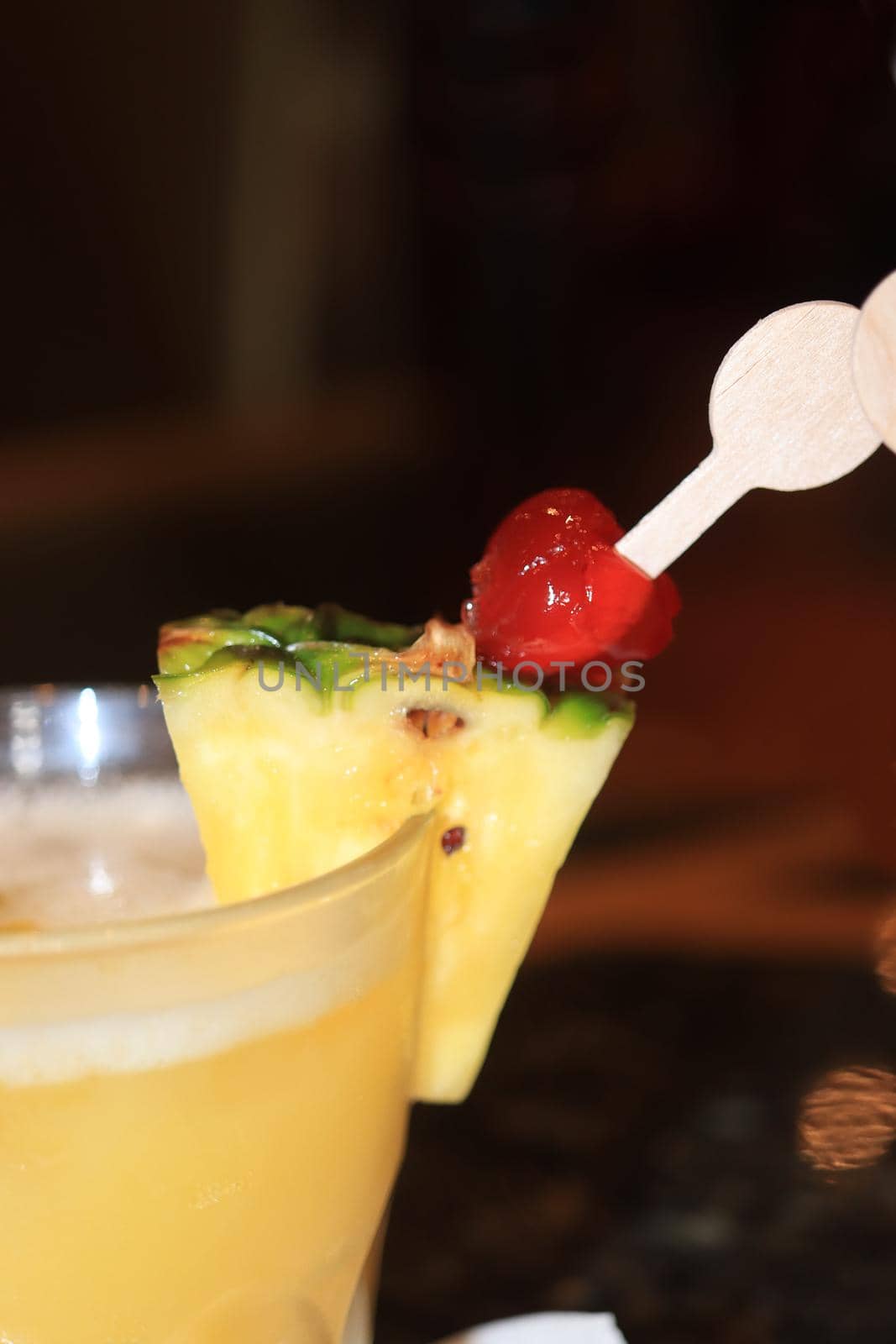 Big glass with a fruity cocktail, decorated with pineapple and cherry. Cruise ship cocktail