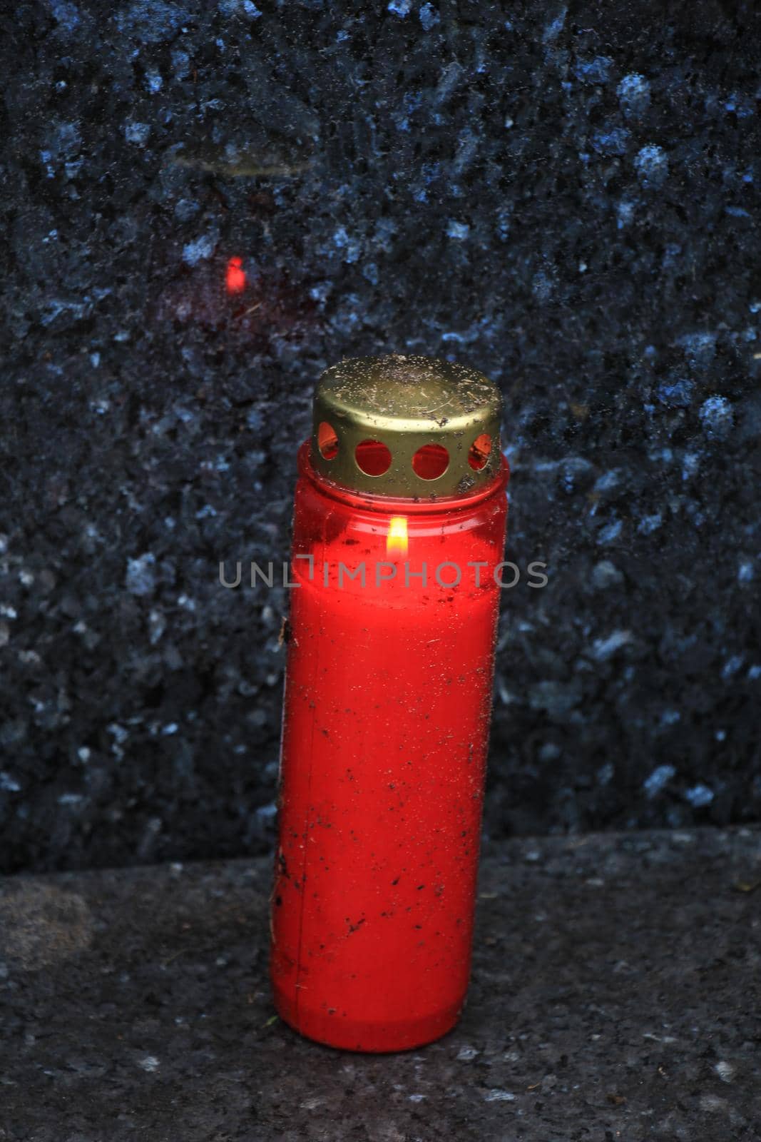 a red, burning candle on a grave