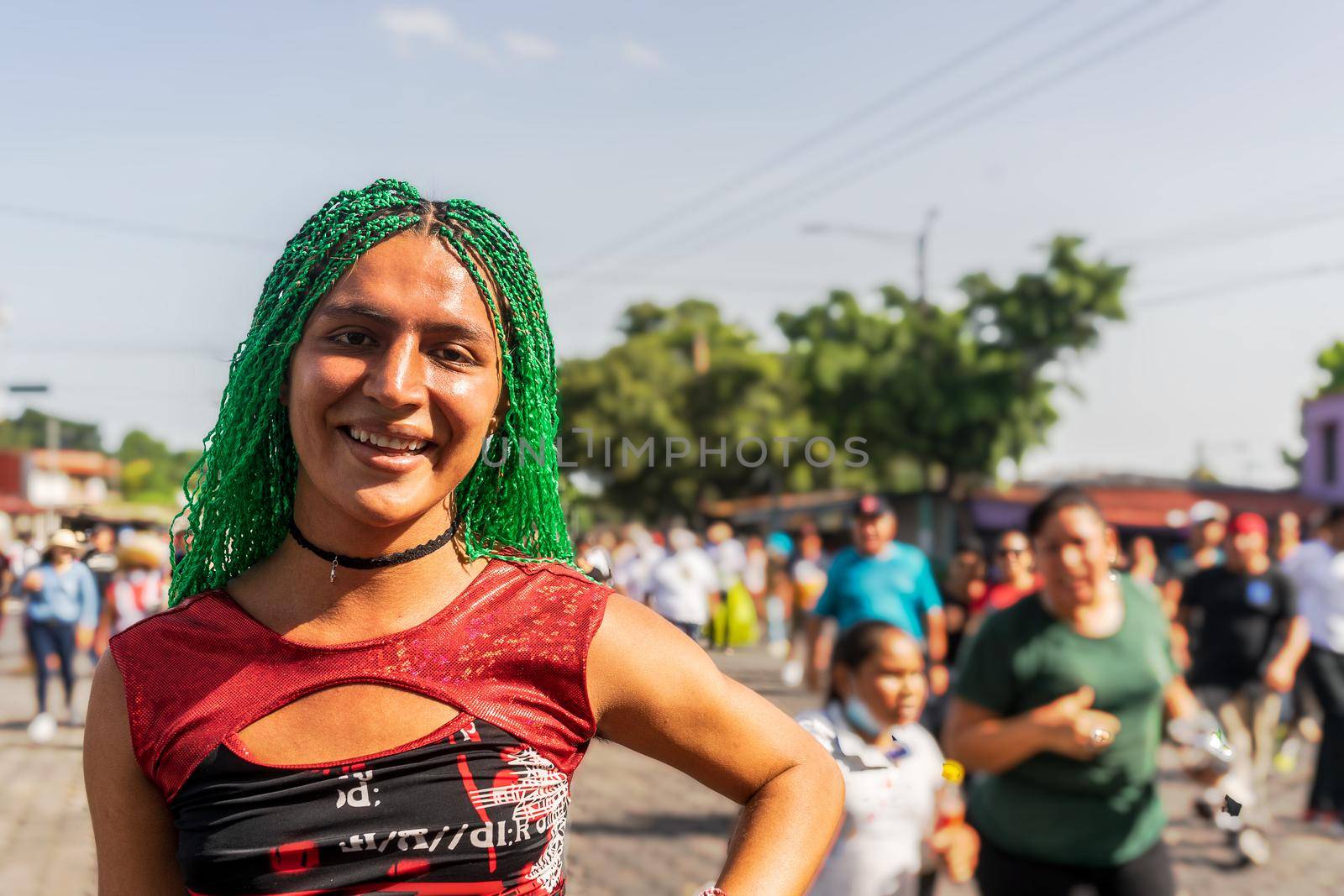 Young Latino gay with green braids outdoors smiling at camera in Managua, Nicaragua