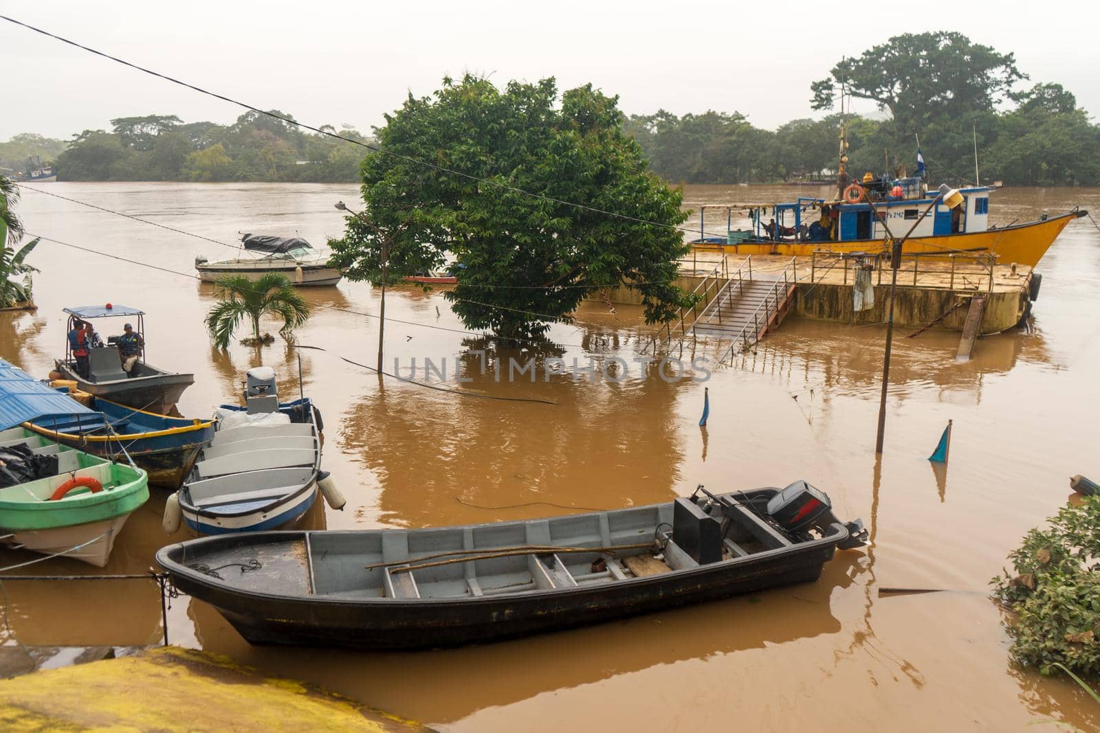 Ships moored at a dock of a muddy river with the flow exceeded due to the rains by cfalvarez