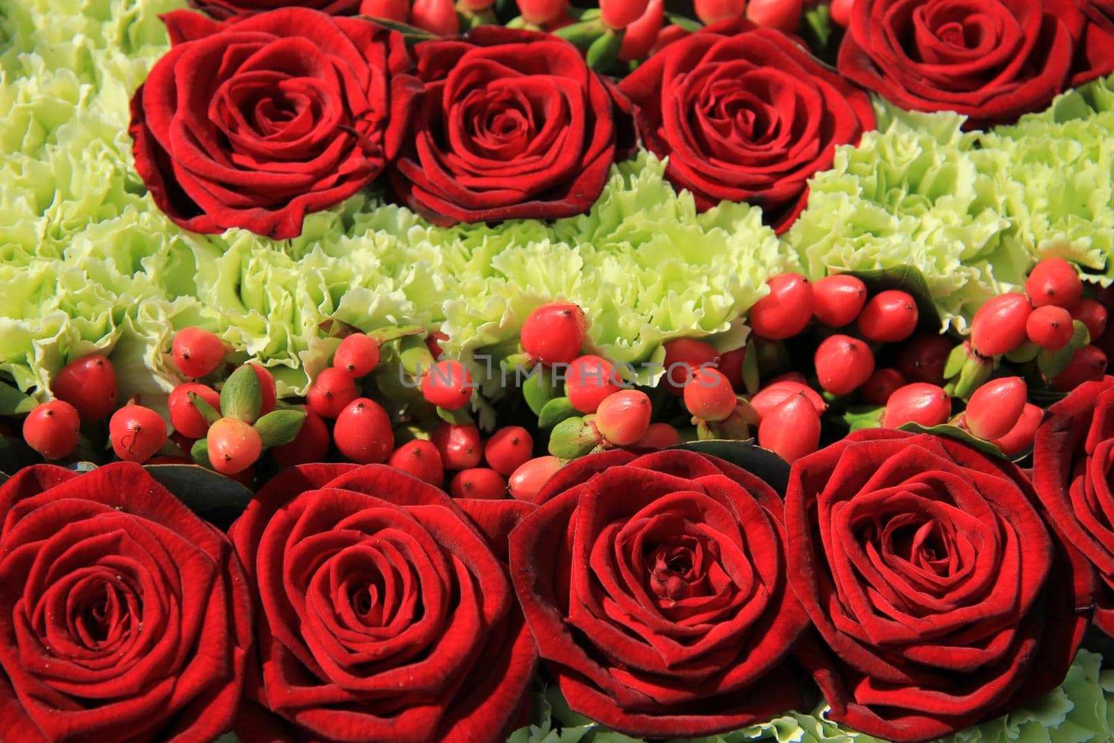 Red rose wedding arrangement with red berries and green white carnations