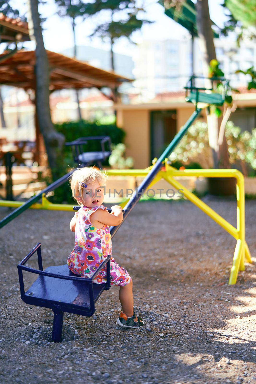 Little girl sits on a teeter-totter with her head turned back. High quality photo