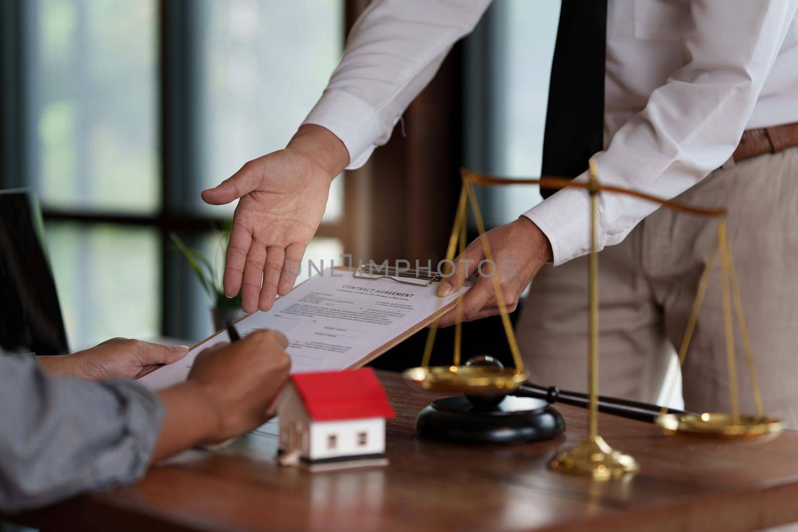 Business person and lawyers discussing contract papers with brass scale on wooden desk in office. Law, legal services, advice, Justice concept. by itchaznong