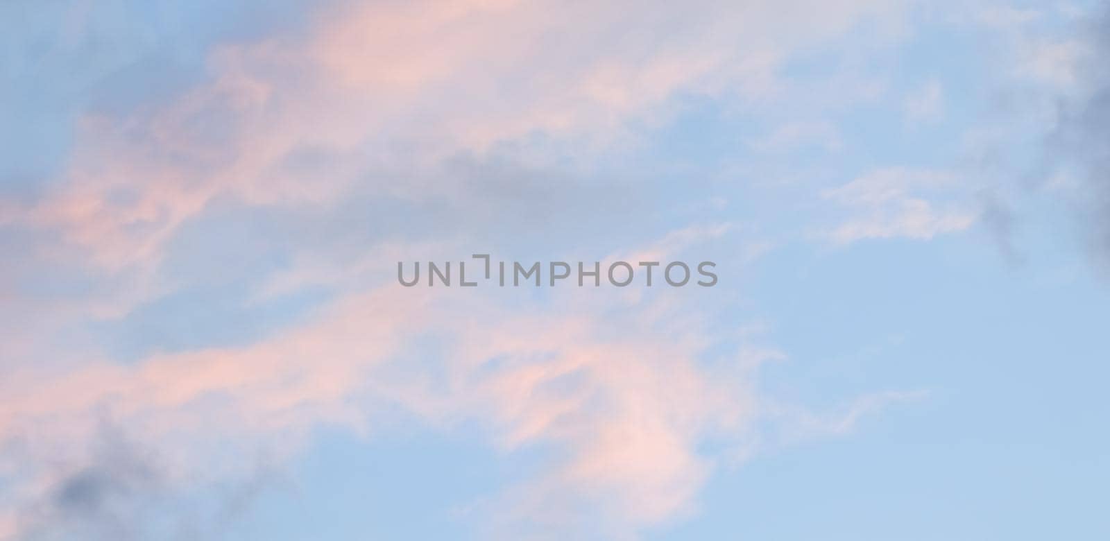 Background of blue sky with pale pink clouds at sunset