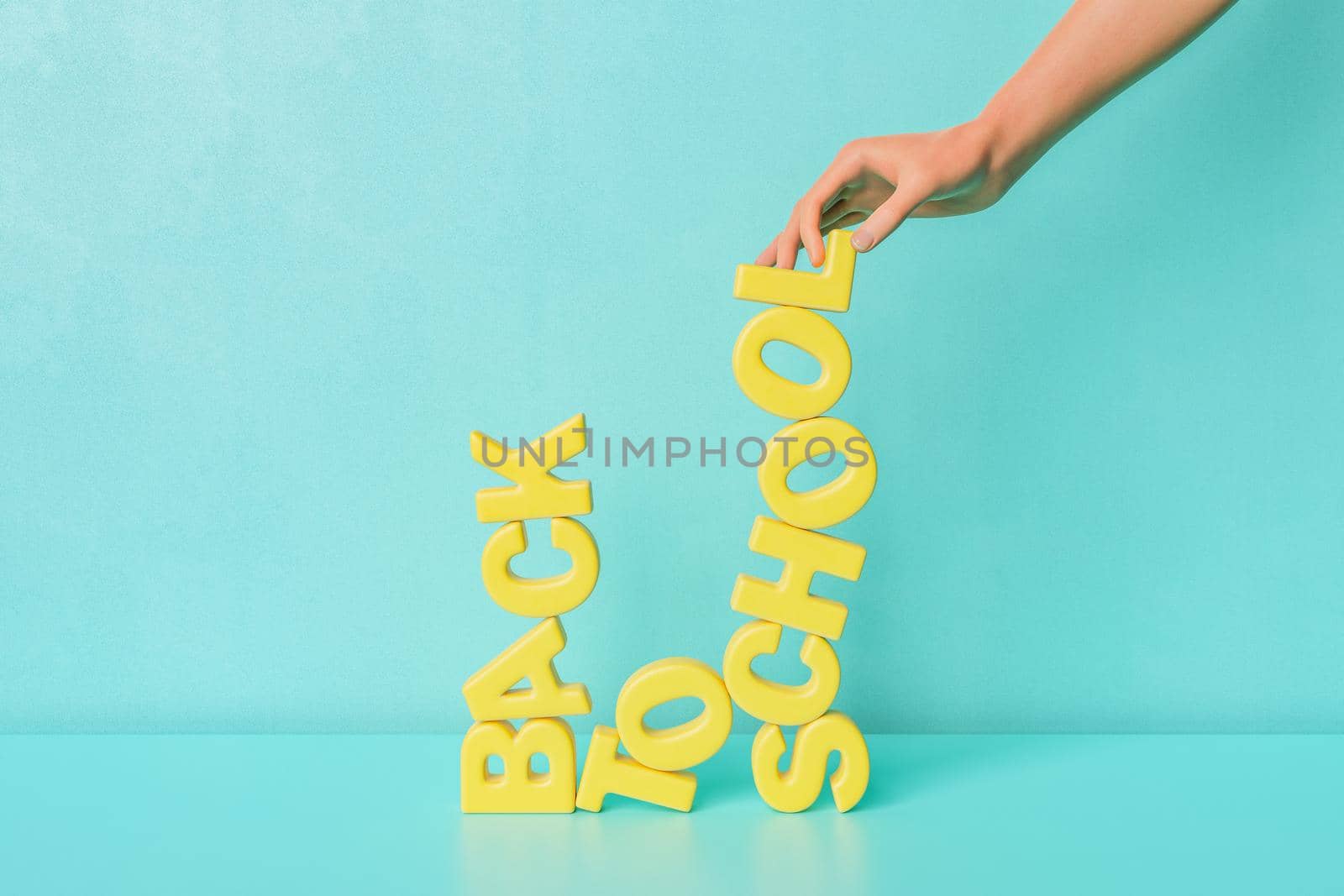 3D rendering of crop unrecognizable person creating Back To School text with yellow letters against blue background