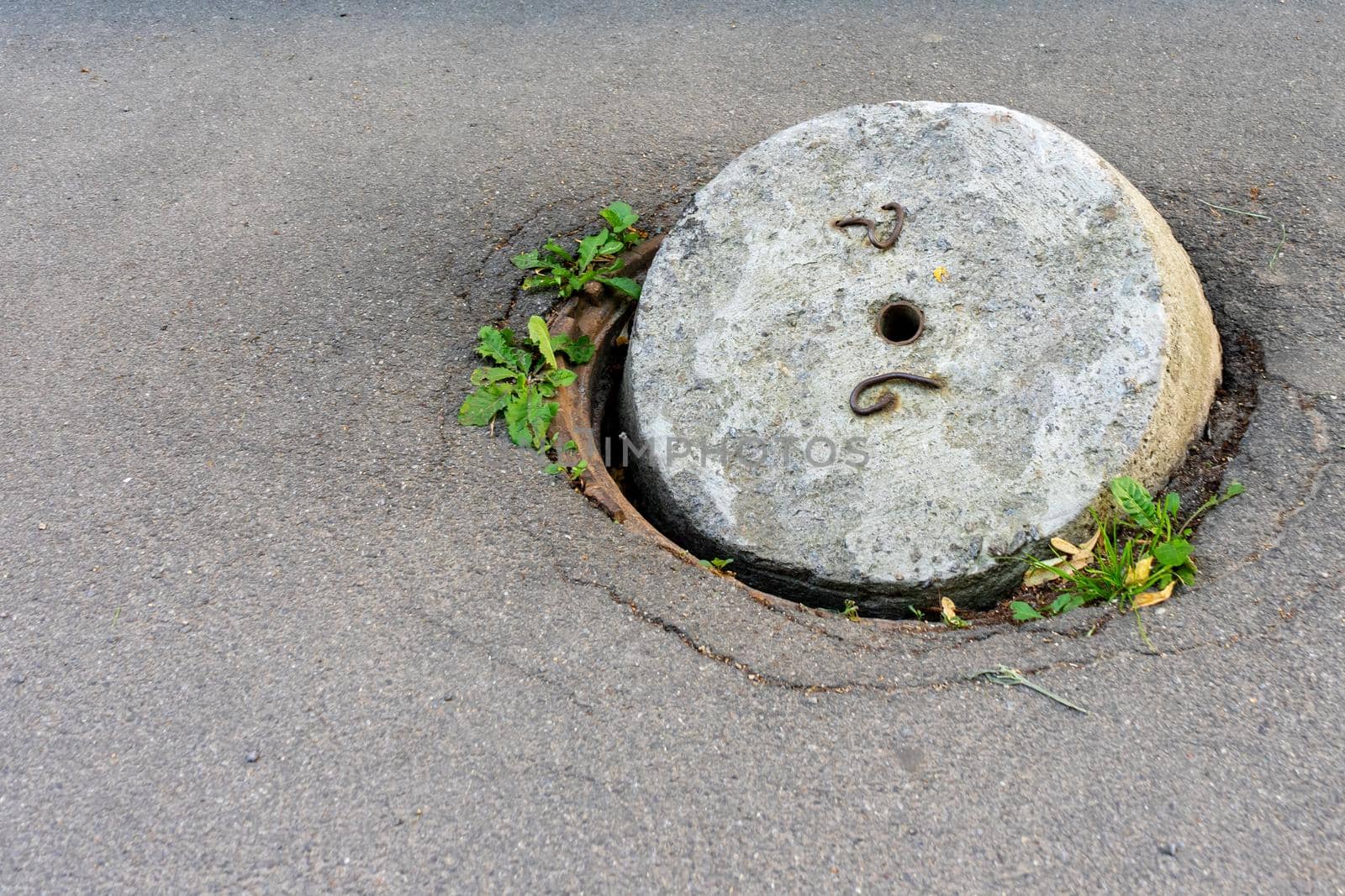 An old sewer manhole with an open concrete cover. Copy space.