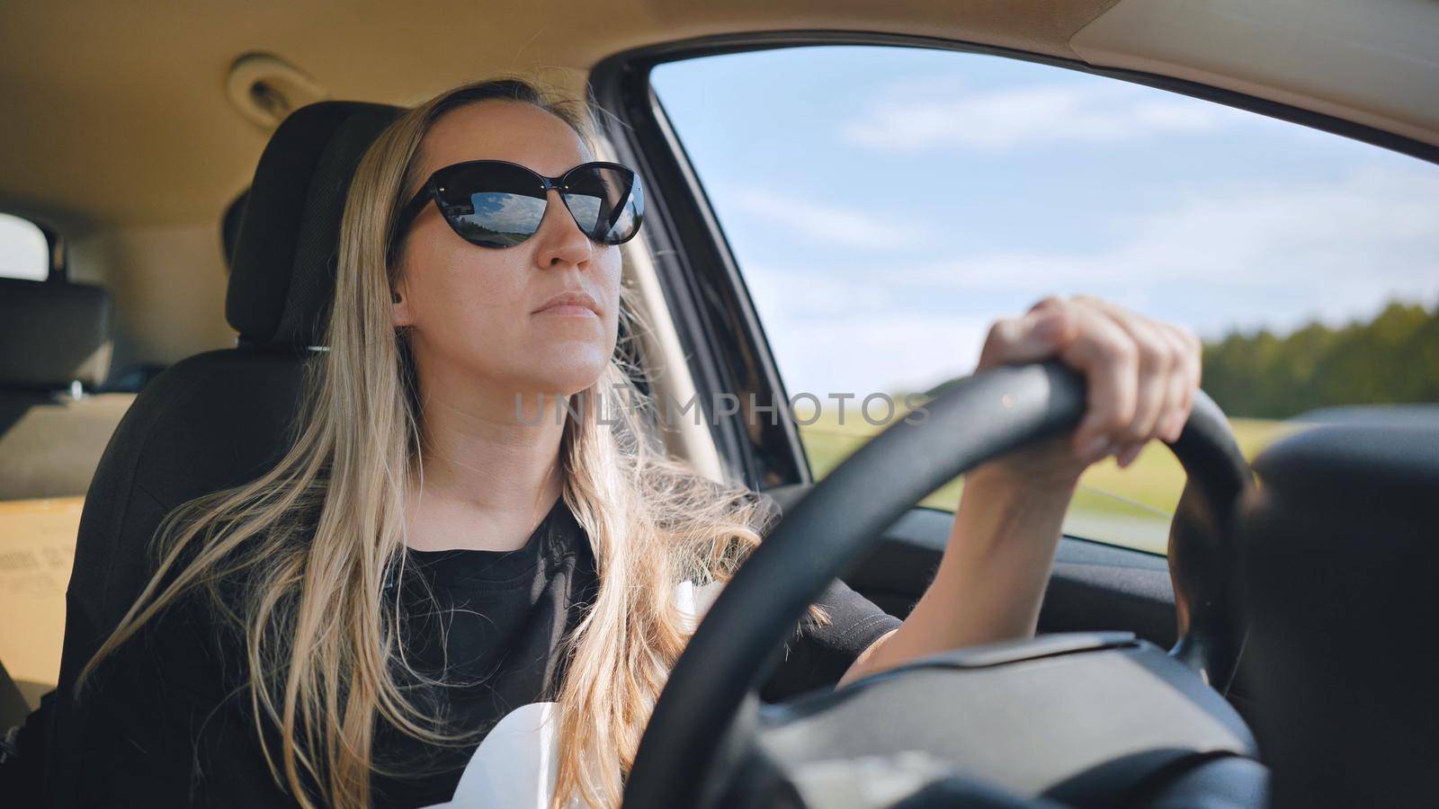 A young woman in a good mood behind the wheel of a car