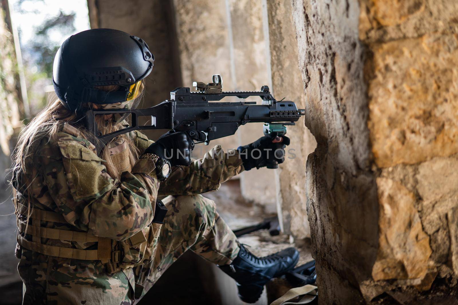 A woman in an army uniform shoots a firearm in an abandoned building