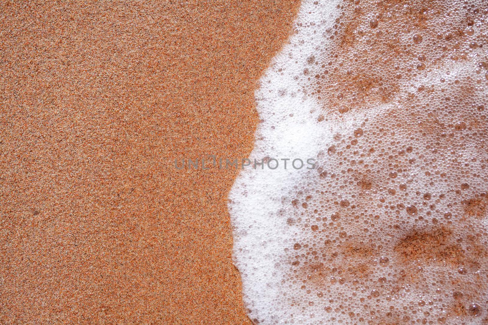 A soft wave runs on a sandy shore on a summer day. Empty space can be used as background for display or montage your top view products.