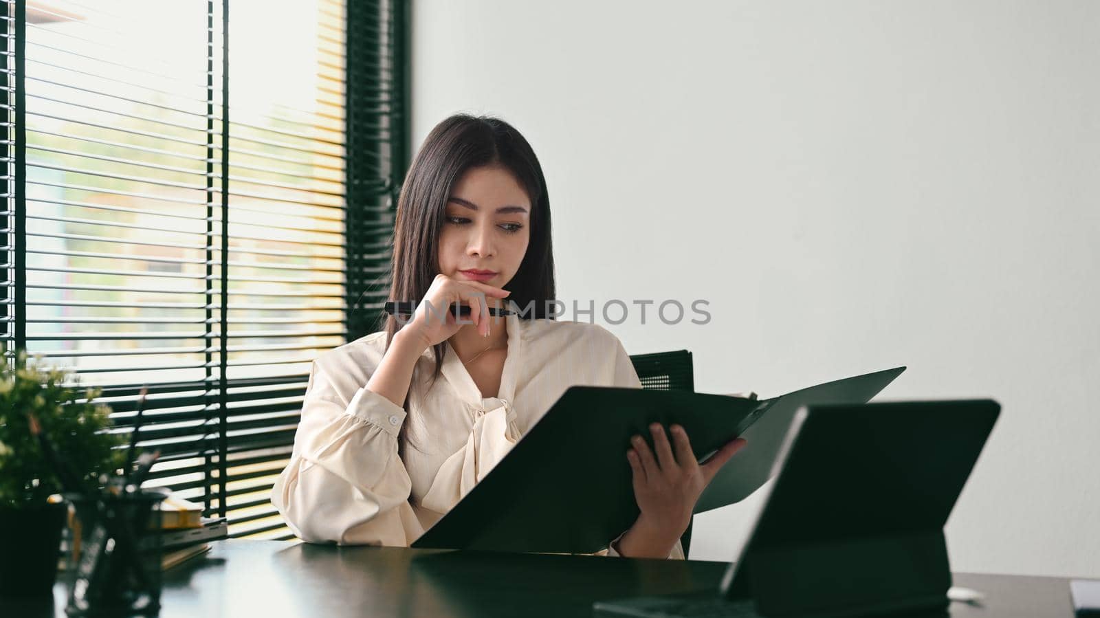 Thoughtful millennial businesswoman reading bank financial loan investment agreement at her workplace by prathanchorruangsak