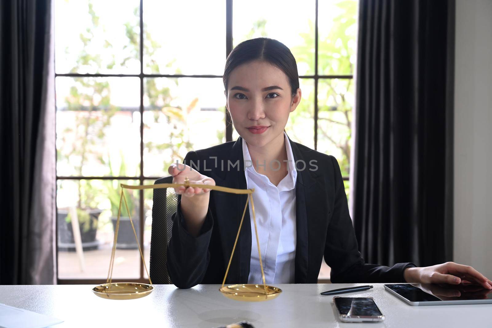 Female lawyers holding brass scale and looking confidently to camera. Lawyer, justice and law and attorney concept by prathanchorruangsak