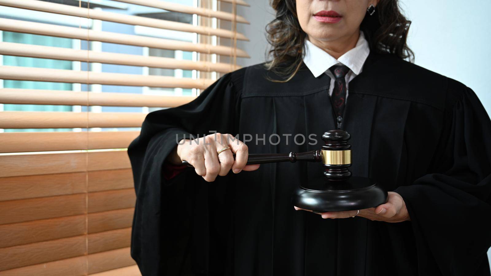 Confident senior judge in robe gown uniform holding a gavel in hands. Lawyer, justice and law and attorney concept by prathanchorruangsak