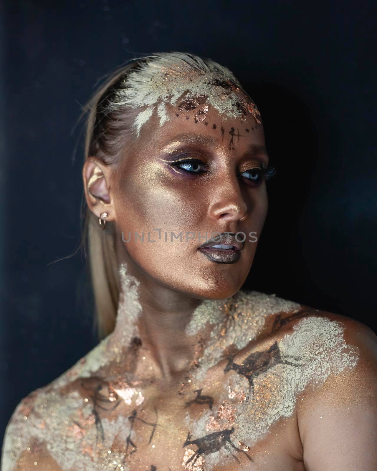 Portrait of female model with creative prehistoric makeup with cave painting