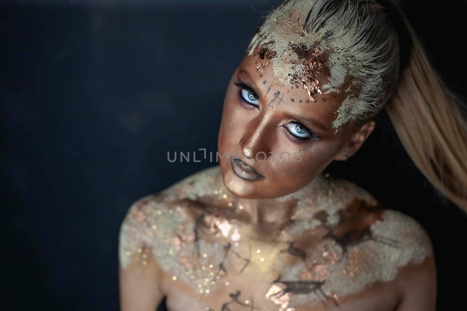 Portrait of female model with creative prehistoric makeup with cave painting