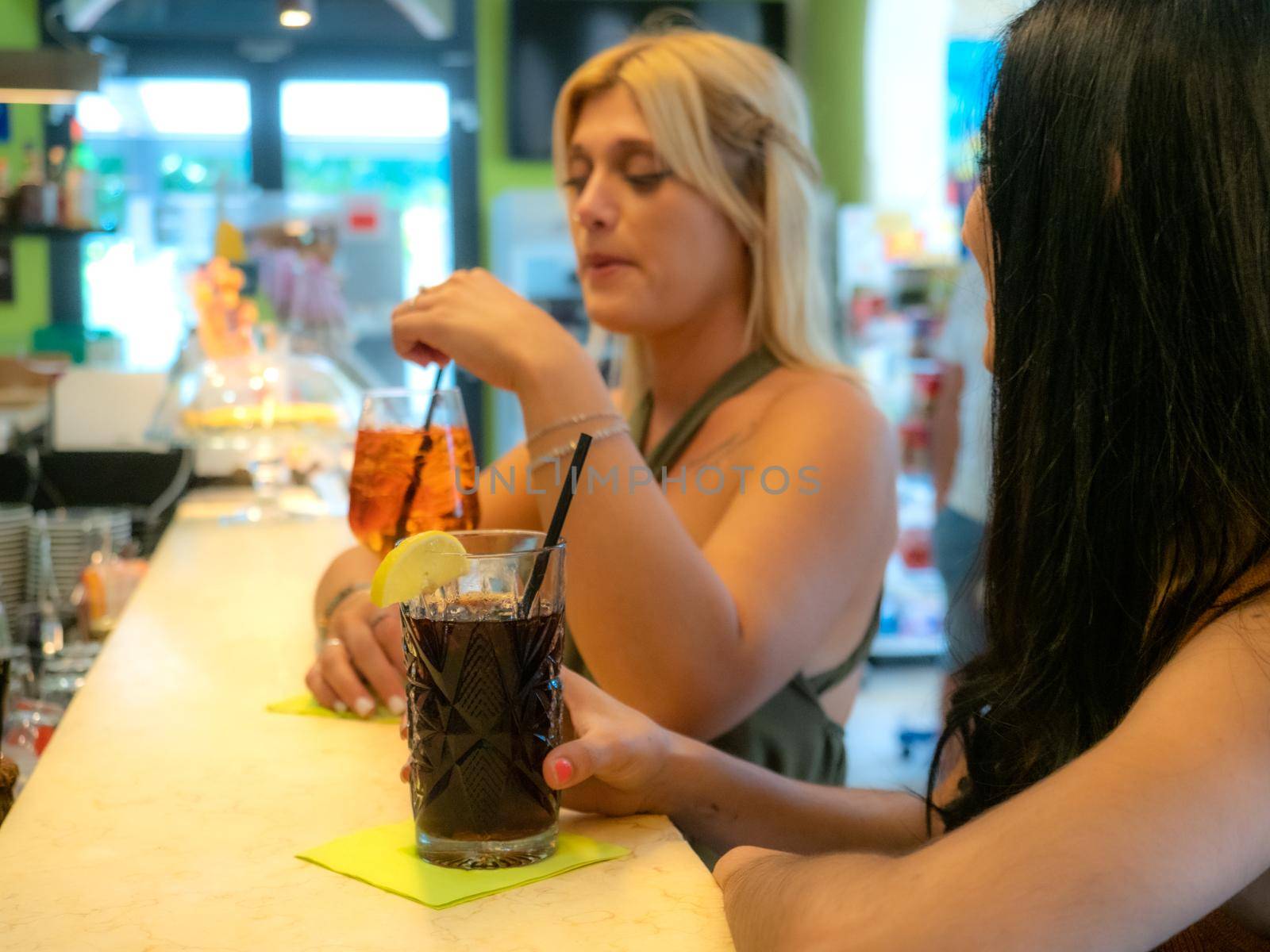 caucasian and latino female friends at the bar drinking spritz and cola libre by verbano