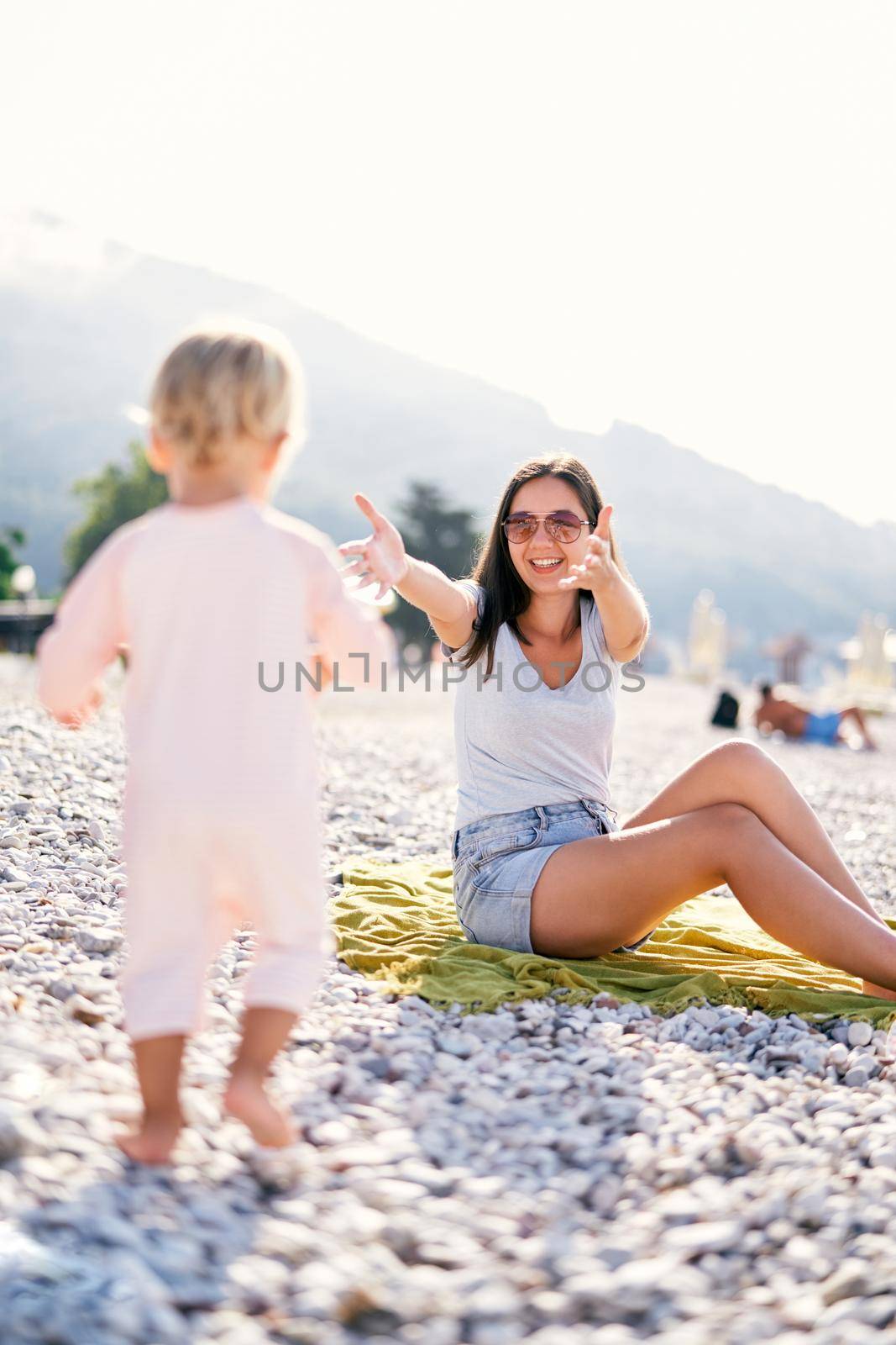 Little girl walks along the beach to her mother open arms. High quality photo
