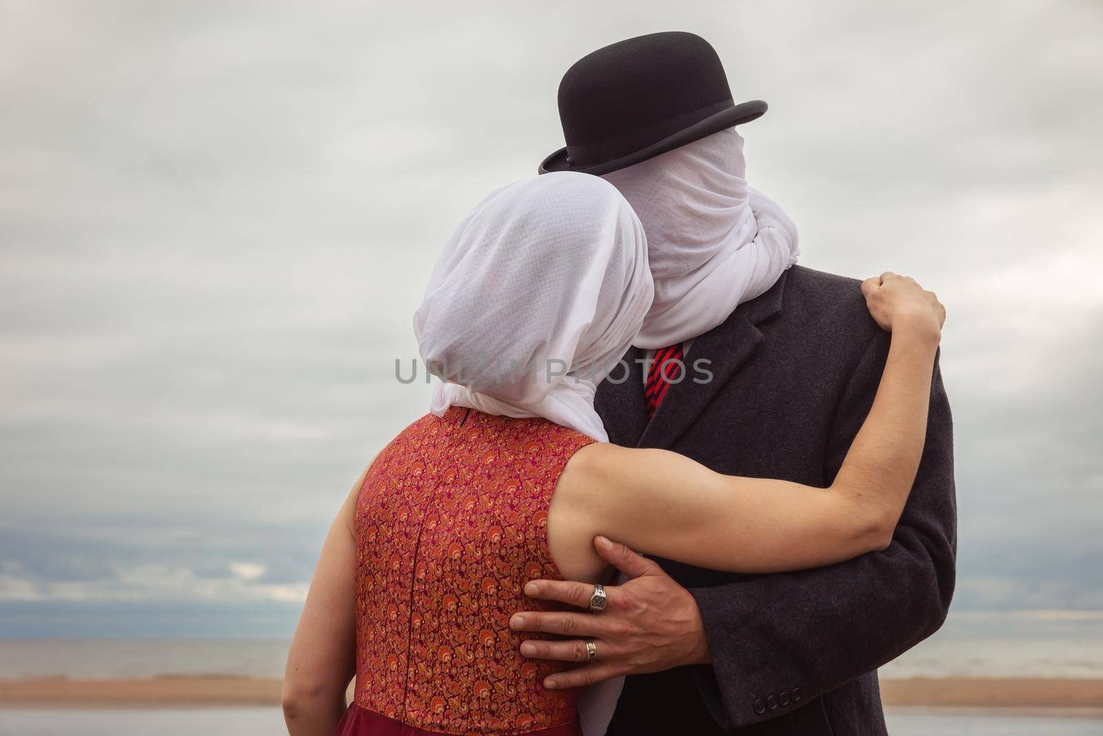 Faceless portrait of man kissing woman with white fabrics on their heads