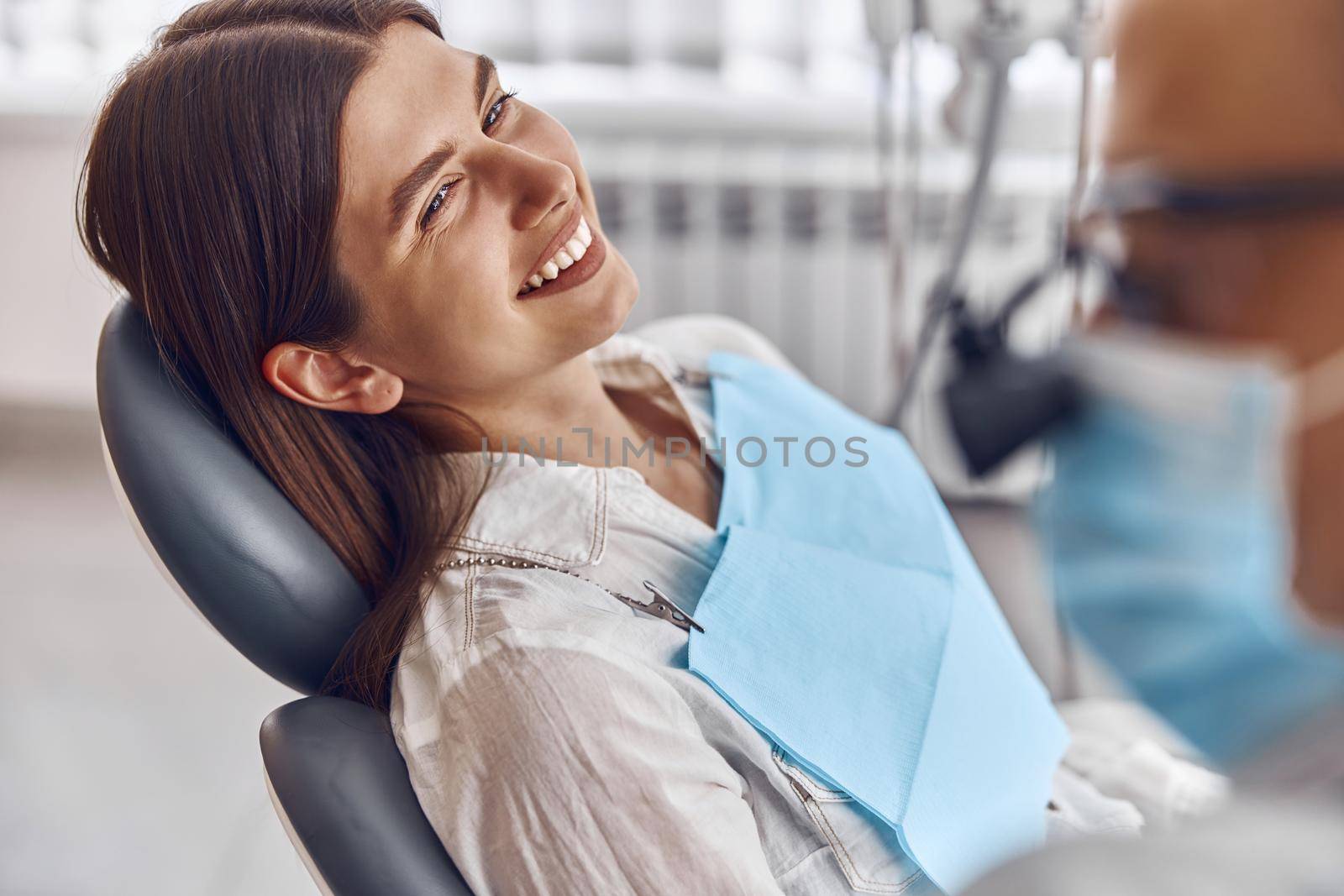 Professional doctor is checking woman's teeth in light modern dental clinic by Yaroslav_astakhov