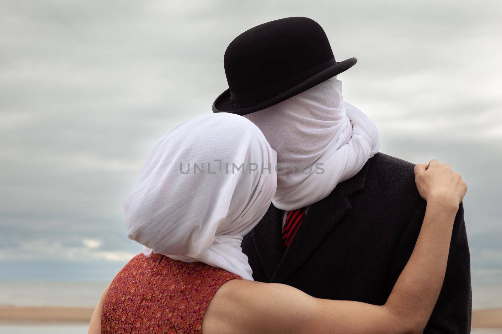 Faceless portrait of man kissing woman with white fabrics on their heads