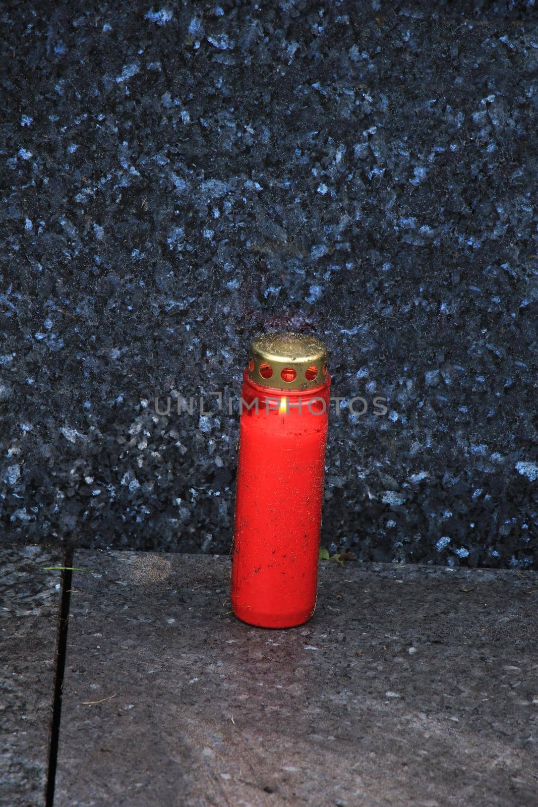 a red, burning candle on a grave