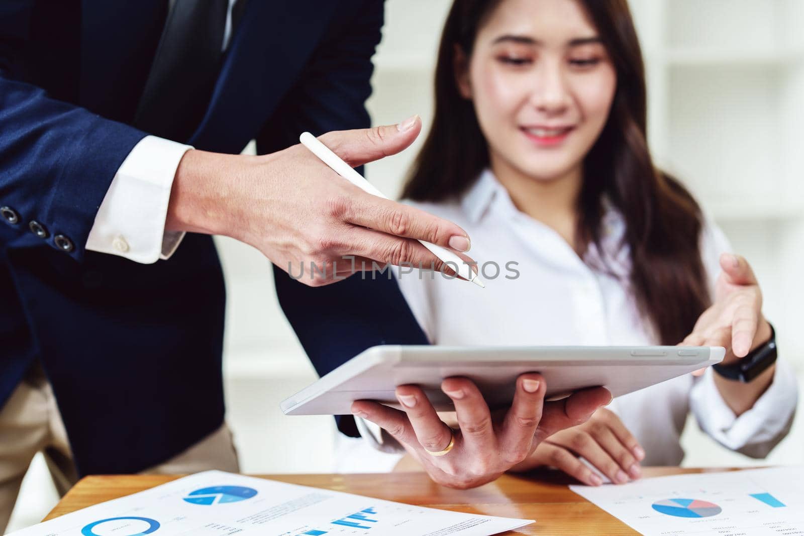 two young Asian businessusing their tablet with documents to plan marketing strategies and investments to profit from their clients.