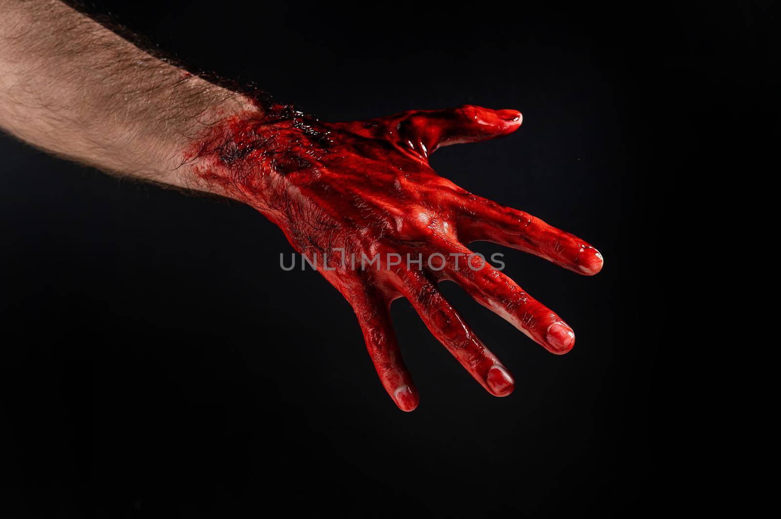 Close-up of a male hand stained with blood on a black background