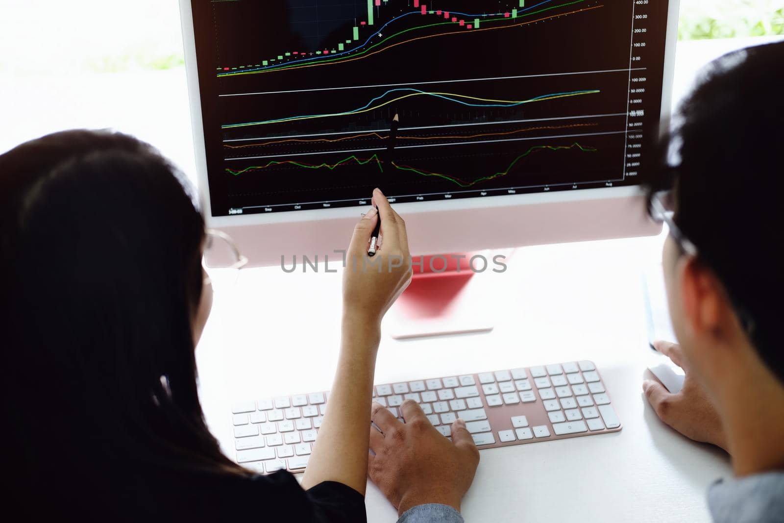 An investment expert points a pen at a tablet monitor to analyze the stock market to teach you how to make a profit