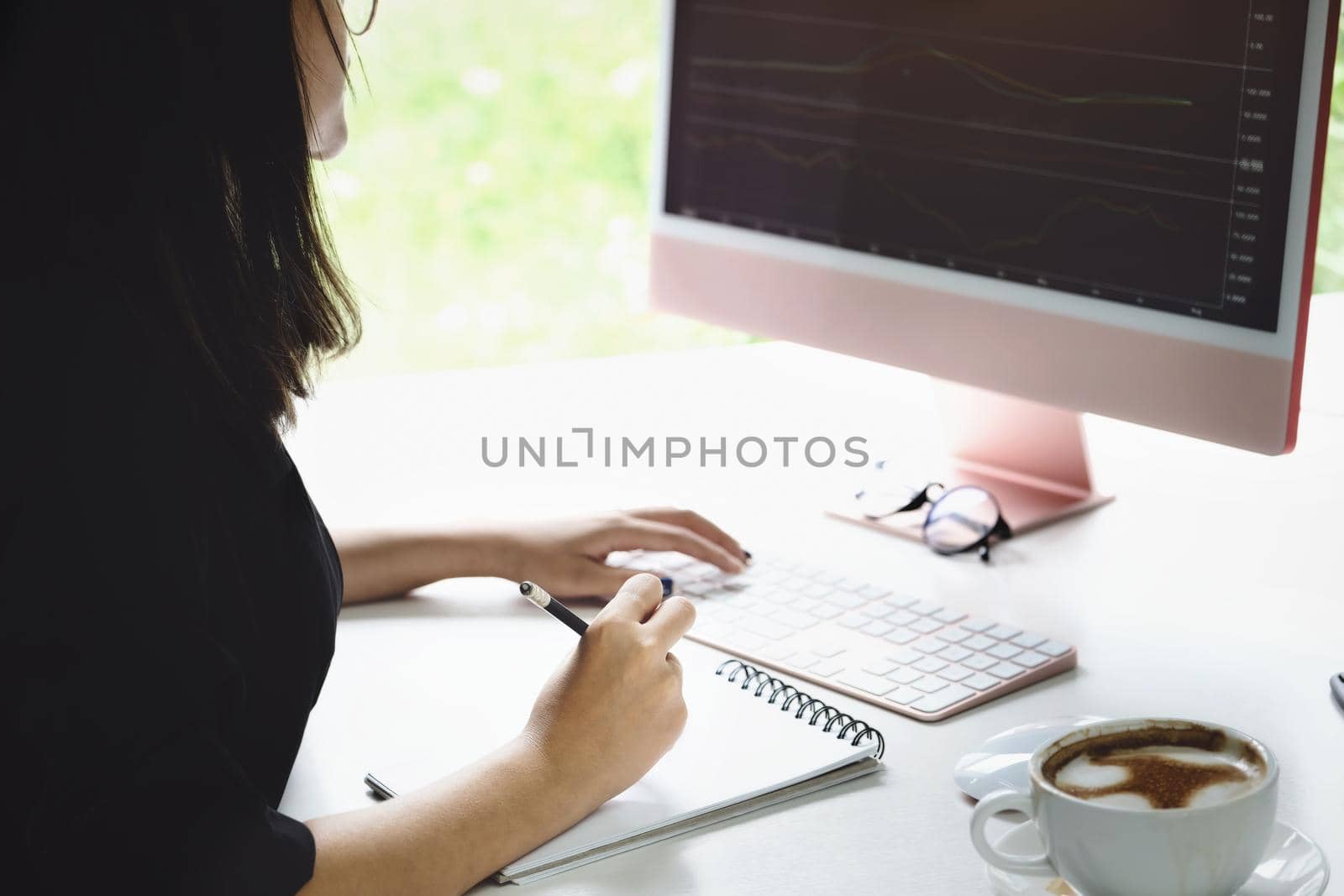 New normal, self-employed women hand holding pen are using notebook and computer laptop to trade stocks for profit, buying and selling