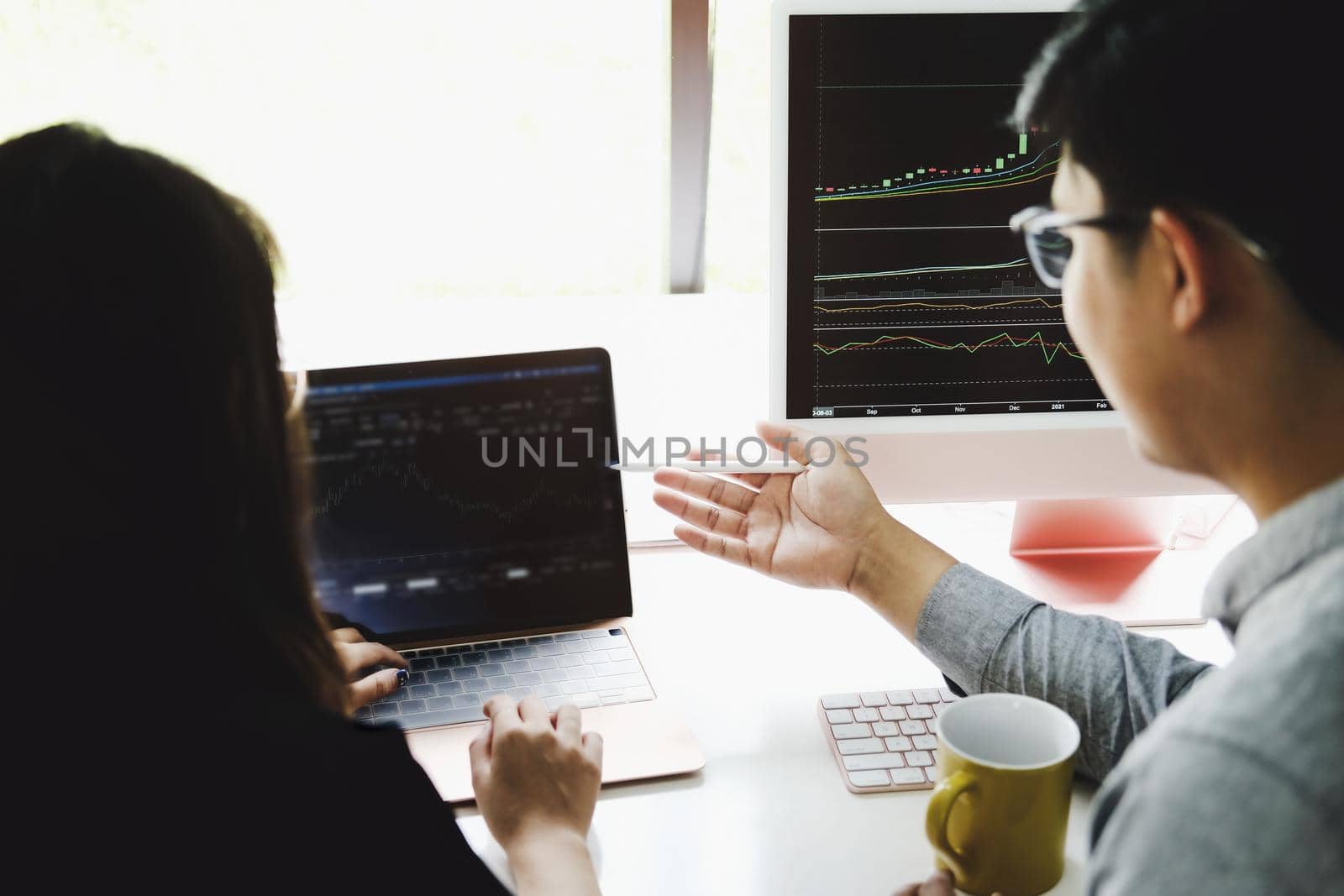 An investment expert points a pen at a computer monitor to analyze the stock market to teach you how to make a profit