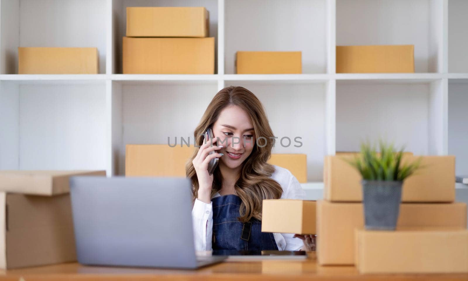 Portrait of young asian business woman talk on smartphone write notebook laptop in home office. Beautiful girl at desk computer take home order. Startup business asia woman online sme telemarketing..