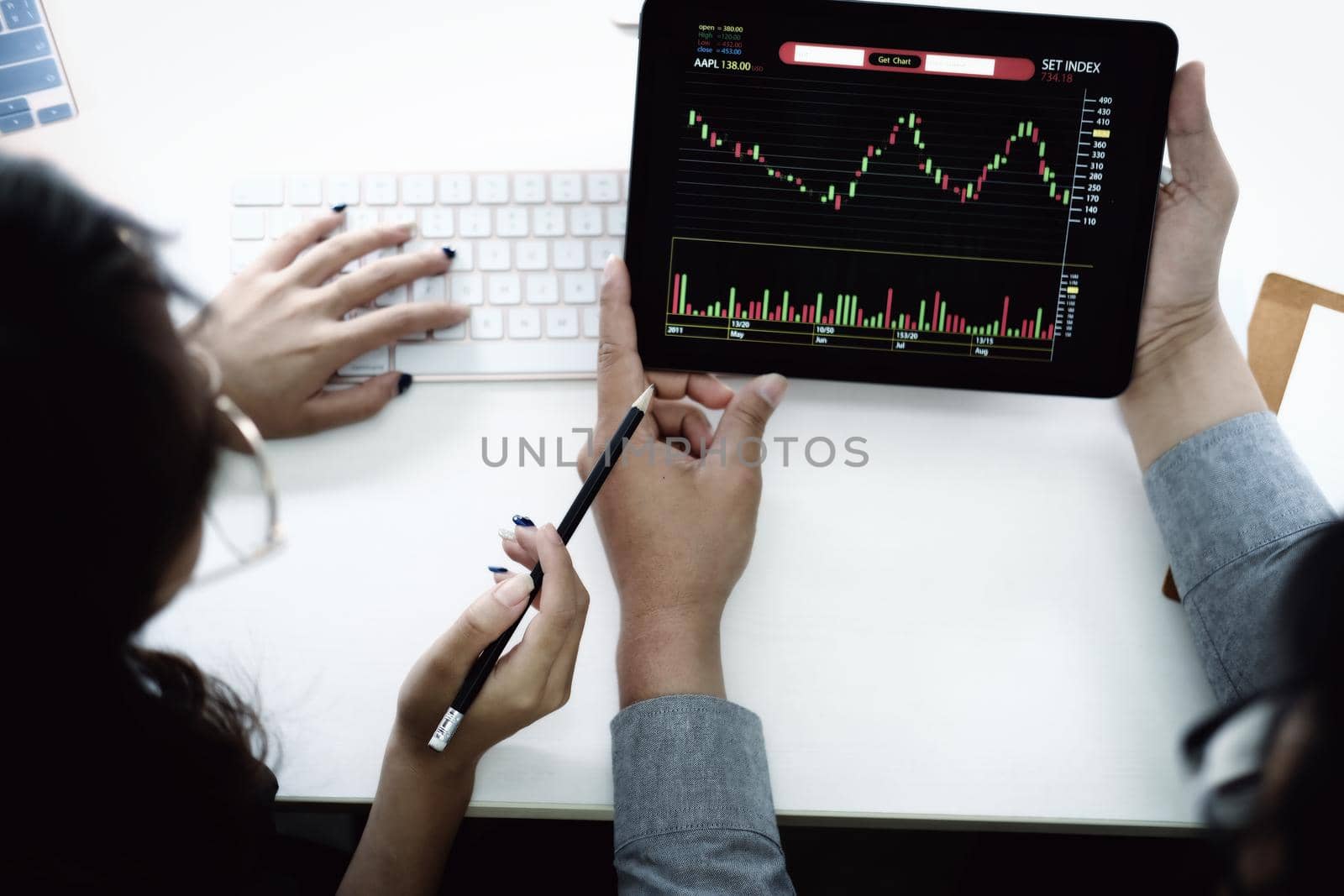 An investment expert points a pen at a tablet monitor to analyze the stock market to teach you how to make a profit