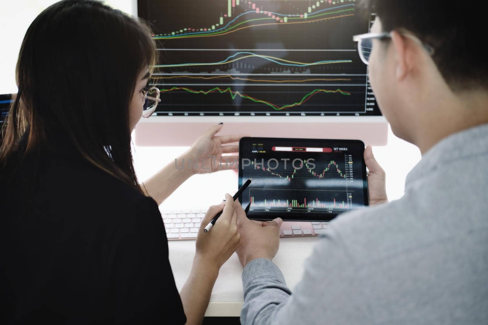 An investment expert points a pen at a tablet monitor to analyze the stock market to teach you how to make a profit