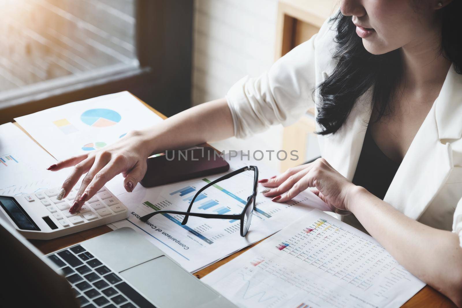 Business woman using calculator to review balance sheet annual using document to calculating budget. audit and Check integrity before investment concept. by Manastrong