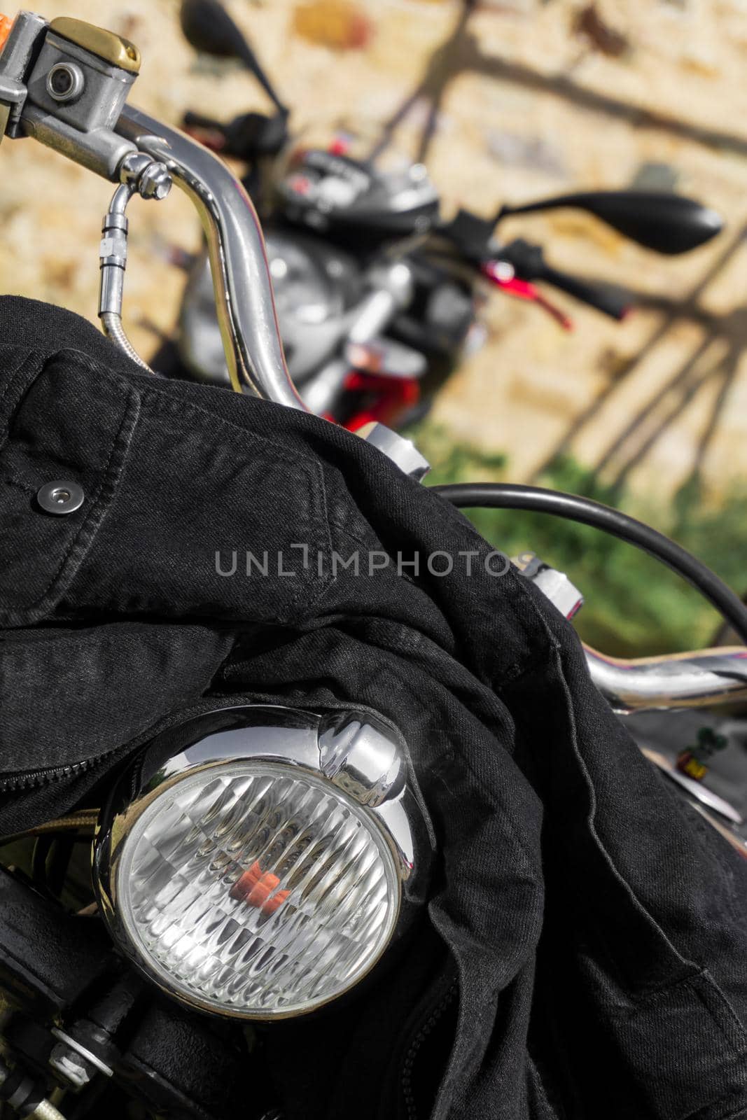 Black denim jacket thrown on the handlebars of a motorcycle close up