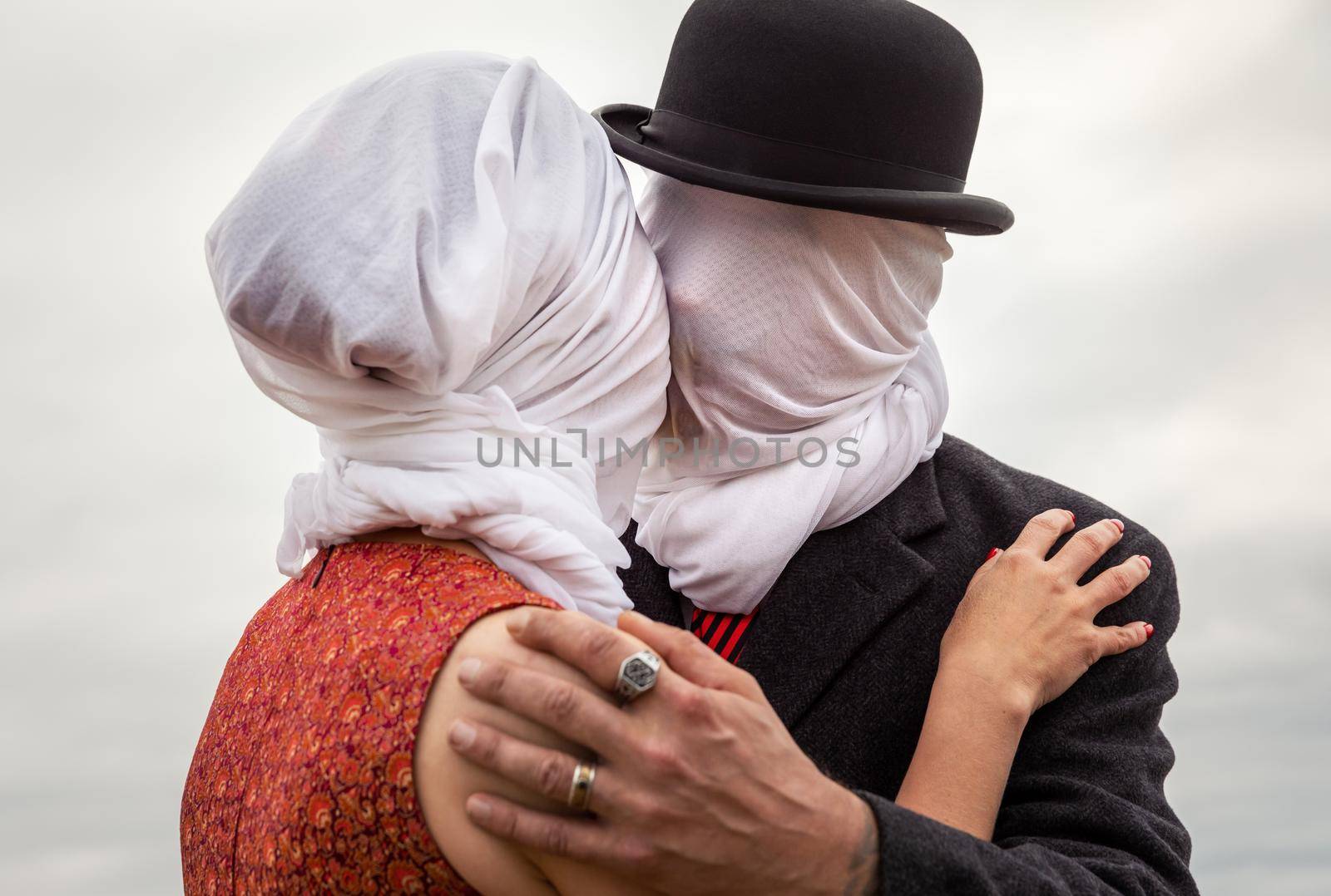 Faceless portrait of man kissing woman with white fabrics on their heads