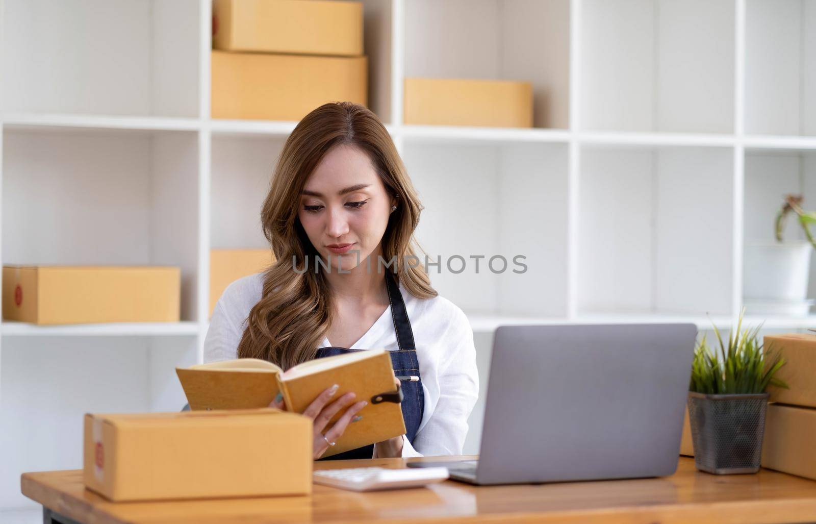 Portrait of Asian young woman SME working with a box at home the workplace.start-up small business owner, small business entrepreneur SME or freelance business online and delivery concept..